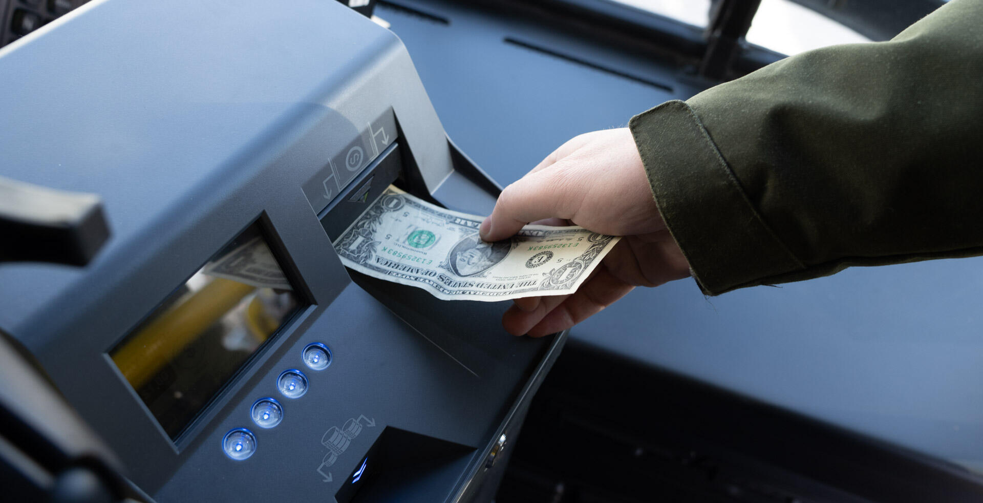 person paying with cash at a bus farebox