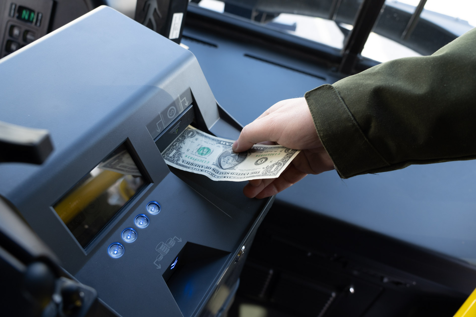 person paying with cash at a bus farebox