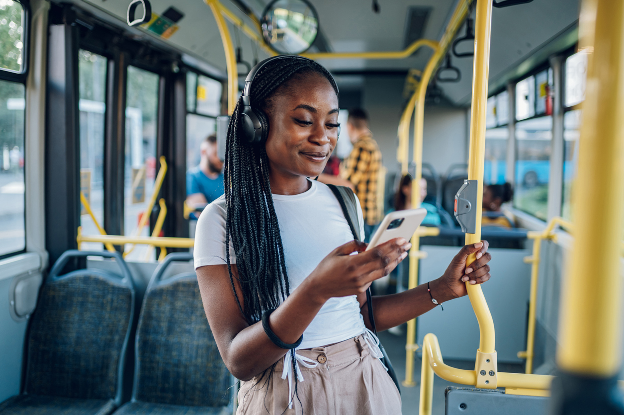 woman standing on a bus looking at her phone