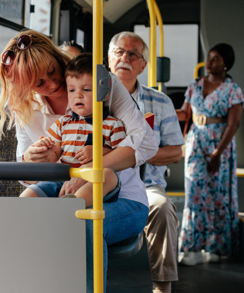 young mom and baby riding a bus with older man and woman in the background