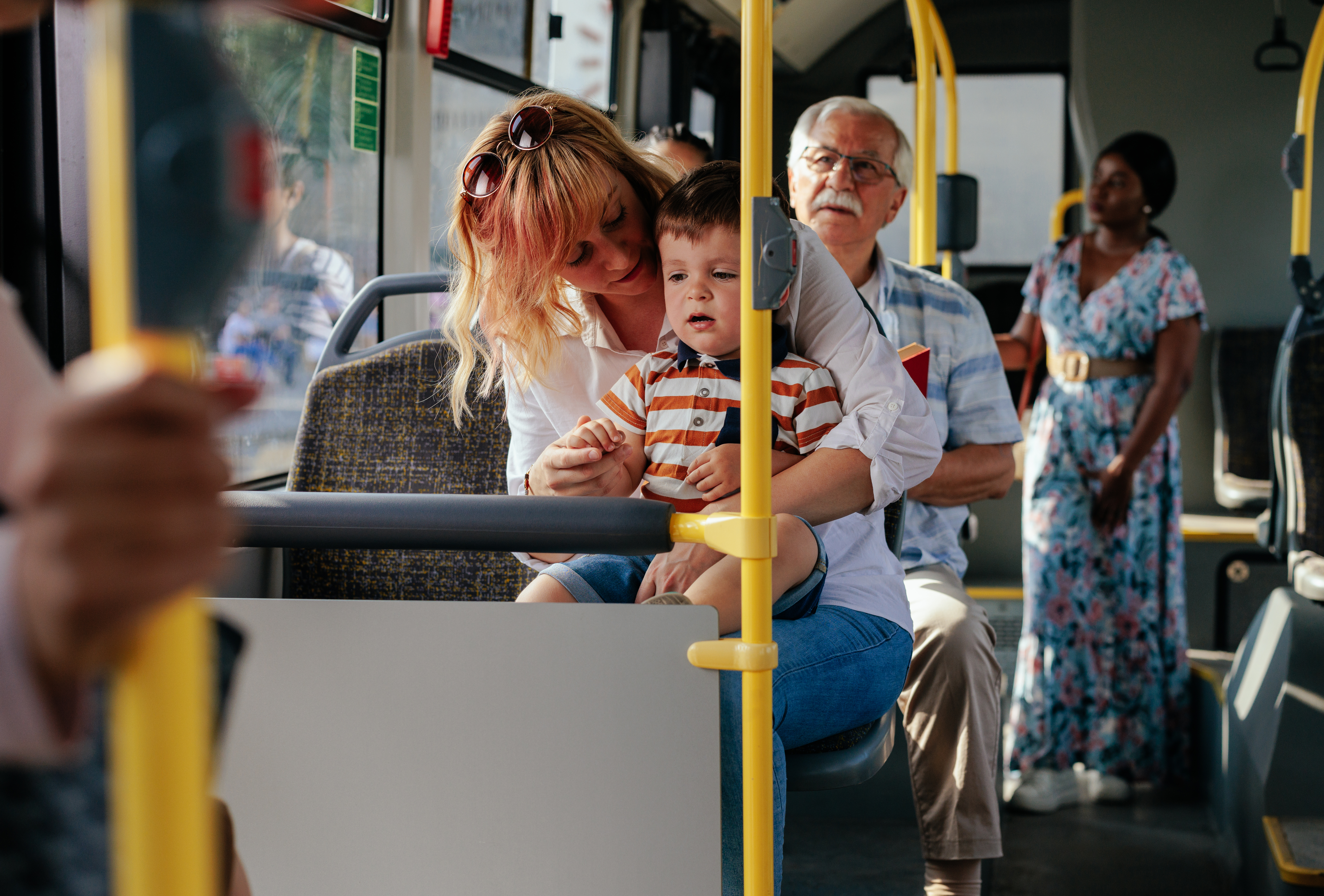 Equitable Mobility Know Your Community young mom and baby riding a bus with older man and woman in the background