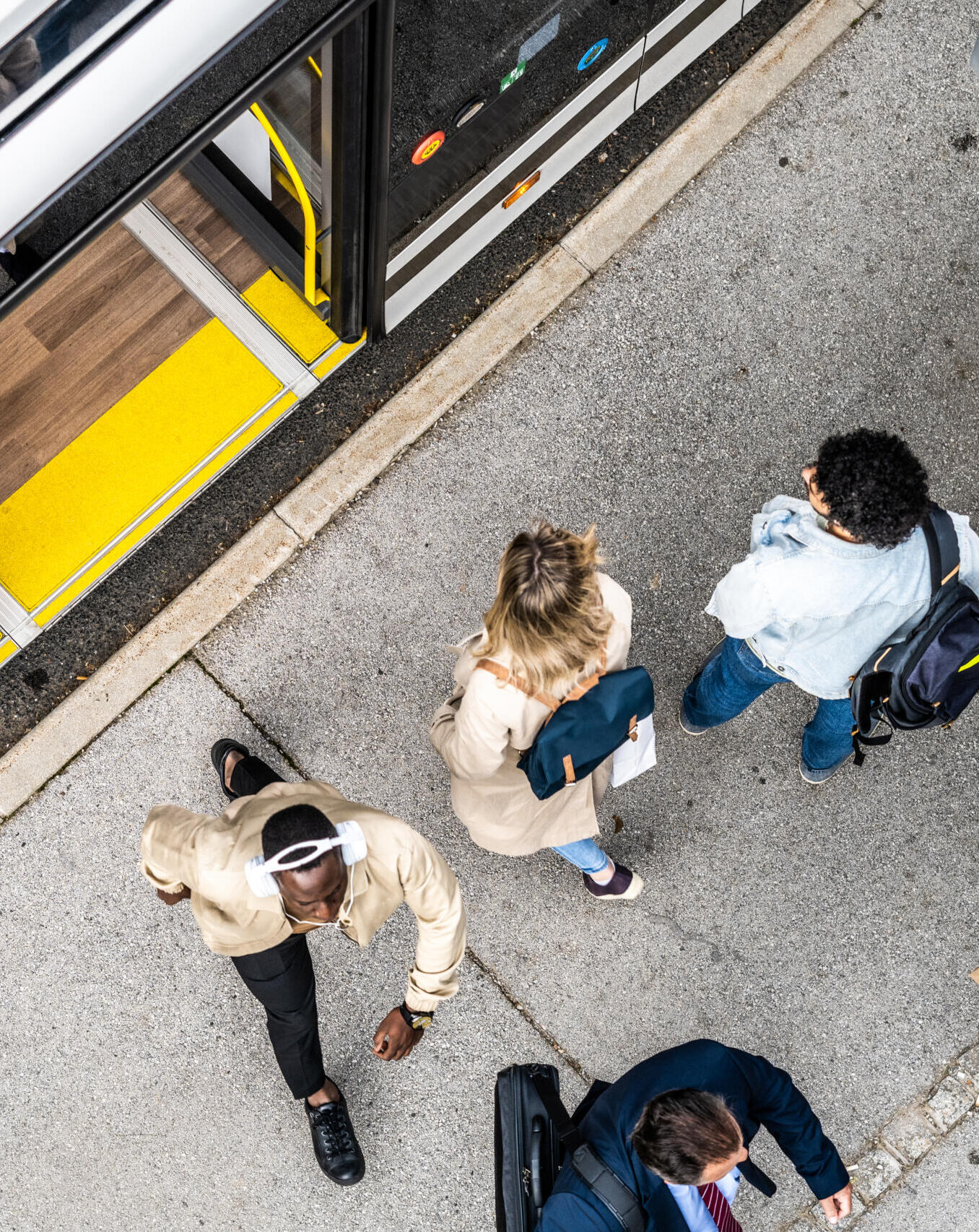 People crowd waiting for city commuter bus at transport stop, top view. Passengers standing and chatting at public vehicle station, scene from above