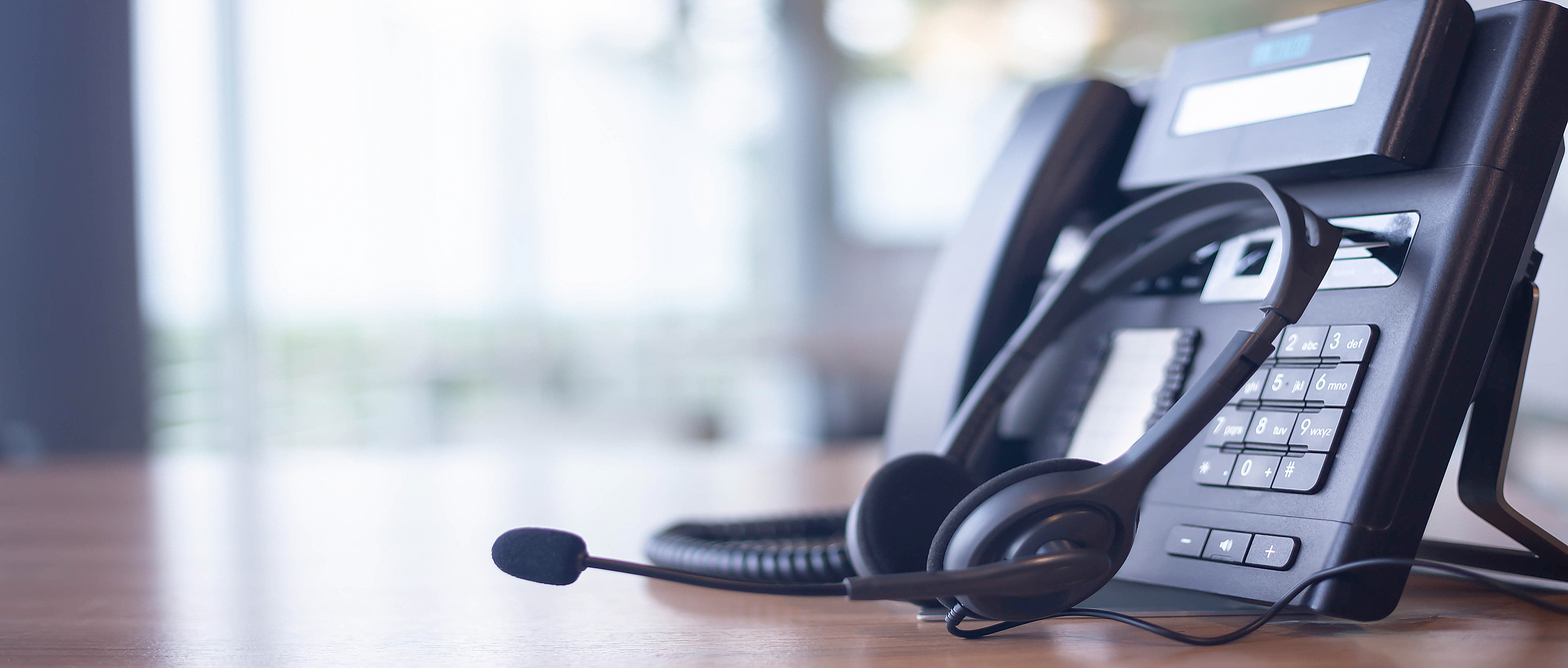Photo of a customer care phone and headset on a desk